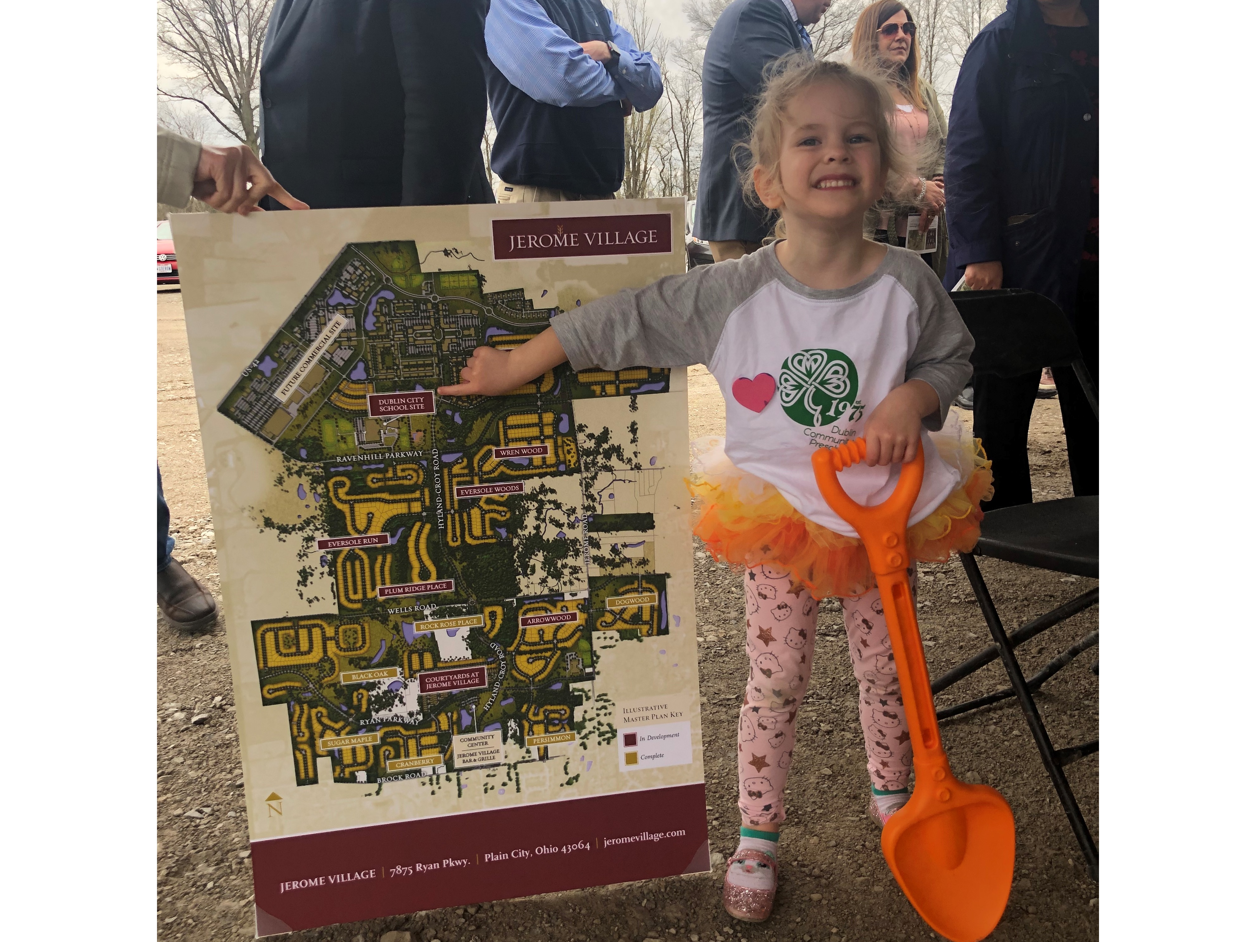 Girl with toy shovel standing next to Jerome Village master plan